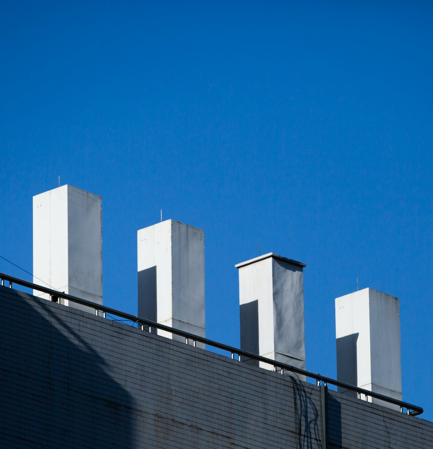 Four ventilation shafts stand on a grey tiled rooftop.